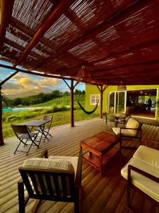 eine Holzterrasse mit Stühlen, einem Tisch und Stühlen in der Unterkunft Chambre Roucou vue Mont Pelée in Le Morne Rouge