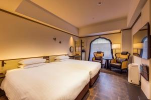 a hotel room with two beds and a chair at Hotel Nikko Kumamoto in Kumamoto