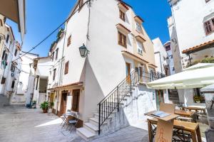 eine Straße mit einem weißen Gebäude und Tischen und Stühlen in der Unterkunft Cecilia in Baška