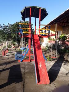 a playground with a red slide and an umbrella at Chalés Rosados in Serra de São Bento