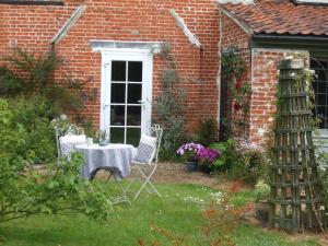 a garden with a table and chairs in front of a brick house at The Old Vicarage Bed And Breakfast in Hindolveston