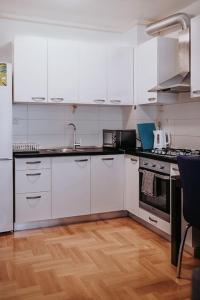 una cucina con armadietti bianchi e pavimenti in legno di Z'Argette Apartment - Free Parking @ Zagrebacka C. a Zagabria