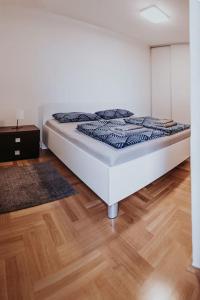 un letto bianco in una camera con pavimento in legno di Z'Argette Apartment - Free Parking @ Zagrebacka C. a Zagabria