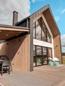 a house with a wooden deck with a patio at Amalkowelove stodoła Kaszuby in Podiazy