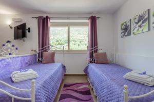 2 camas en una habitación con sábanas moradas y una ventana en Villa Salvatore, en Torretta