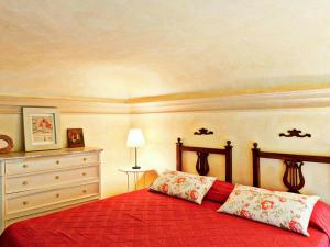 a bedroom with a red bed and a dresser at Charming Elegant castle flat with large garden in Rocca Grimalda
