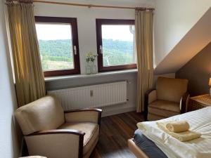 a bedroom with a bed and two chairs and two windows at Apartment Haus Aktiv Top in Winterberg