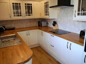 a kitchen with white cabinets and a wooden counter top at Portling View in Dalbeattie