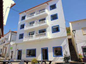 a white building with balconies and tables in front of it at Residencia do Parque in Odeceixe +37 photos