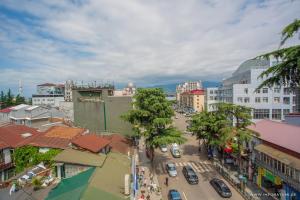 a city street with cars and palm trees and buildings at Hotel Light Palace in Batumi