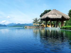 a resort with a large body of water with a thatch roof at Mai Chau Hideaway Lake Resort in Mai Châu