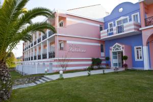 różowo-niebieski budynek z palmą w obiekcie Palatino Hotel w Lixoúrion