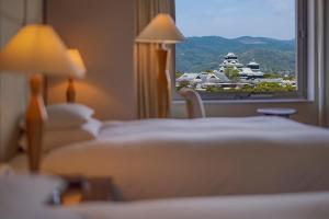 a hotel room with two beds and a window at Hotel Nikko Kumamoto in Kumamoto