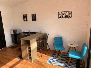 a kitchen with a counter and two blue chairs at Pousada Recanto entre Rios CHALE SOL NASCENTE in Urubici +17 photos