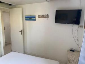 a room with a tv on the wall and a bed at Charmante maisonnette proche plage in Cap d'Agde