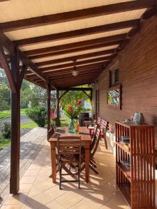 a patio with a table and chairs under a wooden pergola at Le relais de la montagne Pelée in Le Morne Rouge