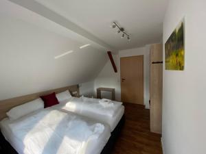 a bedroom with a bed with white sheets and red pillows at Ferienwohnung Zur Rhön Tischlerei in Wiesenthal