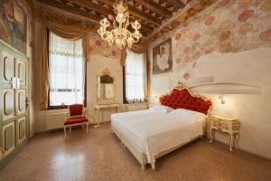 a bedroom with a large white bed and a chandelier at Villa Martin Hotel in Dolo