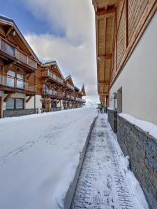 uma rua coberta de neve ao lado de um edifício em Chalet la Cochette em La Toussuire