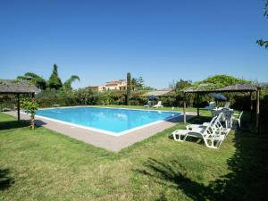 CartabubboにあるHoliday Home in Sciacca with Garden Swimming Pool Parkingの白い椅子とパラソル付きのスイミングプール