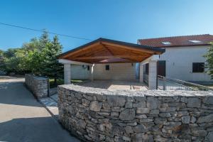 a stone retaining wall with a wooden roof on a house at Country House Dumančić with nice garden and hot tub in Lovreć