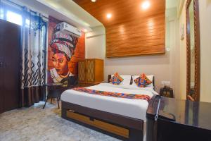 een slaapkamer met een bed met een schilderij aan de muur bij FabExpress Corinthia Boutique Rooms, Candolim Beach in Candolim