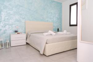 una camera con un letto bianco e una parete blu di Il Sorriso B&B a Ugento