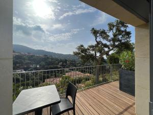 terraza de madera con mesa y sillas en el balcón en Villa l’écrin du Rayol en Rayol-Canadel-sur-Mer