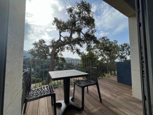 une table et deux chaises sur une terrasse avec un arbre dans l'établissement Villa l’écrin du Rayol, à Rayol-Canadel-sur-Mer