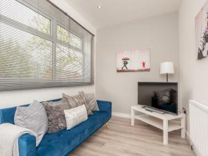 a living room with a blue couch and a tv at Spacious Retreat near city centre Pass the Keys in Leeds