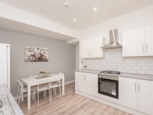 a kitchen with white cabinets and a white table and a table and chairs at Spacious Retreat near city centre Pass the Keys in Leeds