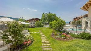 einen Hinterhof mit einem Garten mit Blumen und einem Pool in der Unterkunft Blu Hotel Natura & Spa - Adults Only in Folgaria