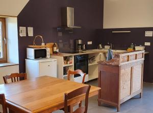 a kitchen with a wooden table and a microwave at L'Oseraie du Quercy in Calvignac