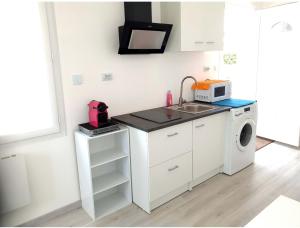 a white kitchen with a sink and a washing machine at Beau logement avec terrasse, jacuzzi et terrain de pétanque privatif à 5 minutes de la plage in Audenge