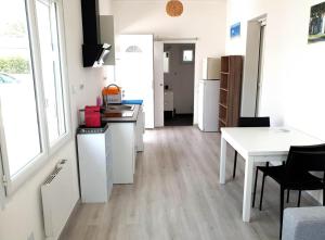 a kitchen with white cabinets and a table and a table at Beau logement avec terrasse, jacuzzi et terrain de pétanque privatif à 5 minutes de la plage in Audenge +1 photo