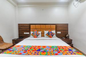 Un dormitorio con una cama con una colcha colorida. en FabHotel Bless Inn, en Allahābād