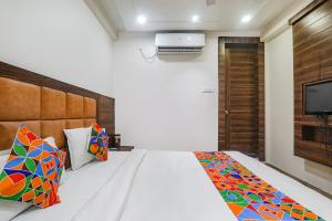 1 dormitorio con 1 cama y TV en la pared en FabHotel Bless Inn, en Allahābād