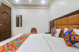 1 dormitorio con 1 cama grande y almohadas coloridas en FabHotel Bless Inn, en Allahābād