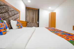 1 dormitorio con 1 cama blanca grande con almohadas coloridas en FabHotel Silver Inn, en Ahmedabad