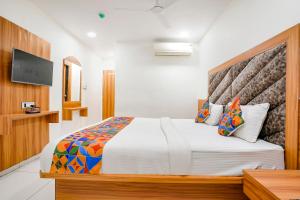 1 dormitorio con 1 cama grande y TV en FabHotel Silver Inn, en Ahmedabad