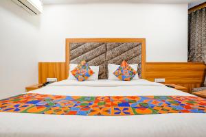 1 dormitorio con 1 cama grande y edredón colorido en FabHotel Silver Inn, en Ahmedabad