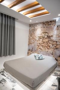 Posto letto in camera con parete in pietra. di Katerina Roza Studios a Naxos Chora