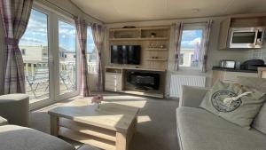 a living room with a couch and a tv and a table at 3 Bedroom Caravan in Tattershall lakes Holiday Park in Tattershall