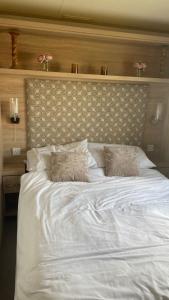 a large white bed with two pillows on it at 3 Bedroom Caravan in Tattershall lakes Holiday Park in Tattershall