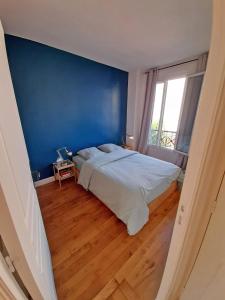 a bedroom with a large bed and a blue wall at Très beau 2P avec vaste séjour ensoleillé - A 50 m du métro du marché et de la mairie in Clichy