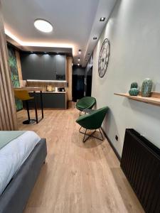 a bedroom with a bed and a kitchen with a clock on the wall at Apartament SPOT Klonowa in Kielce