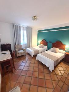 a hotel room with two beds and a chair at Hotel Don Gonzalo in Montilla