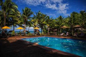 a swimming pool with palm trees and the ocean at Le Vasa Resort in Fuailalo