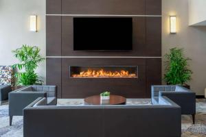 a lobby with a fireplace with a tv on a wall at Wyndham Indianapolis West in Indianapolis