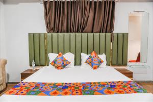 a bedroom with a white bed with colorful pillows at FabHotel Royale Celebrations in Surat